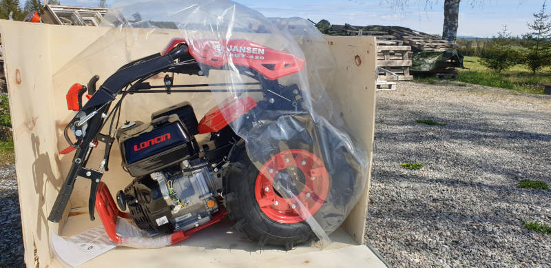 The red Jansen two-wheel tractor still wrapped in plastic inside its wooden shipping crate